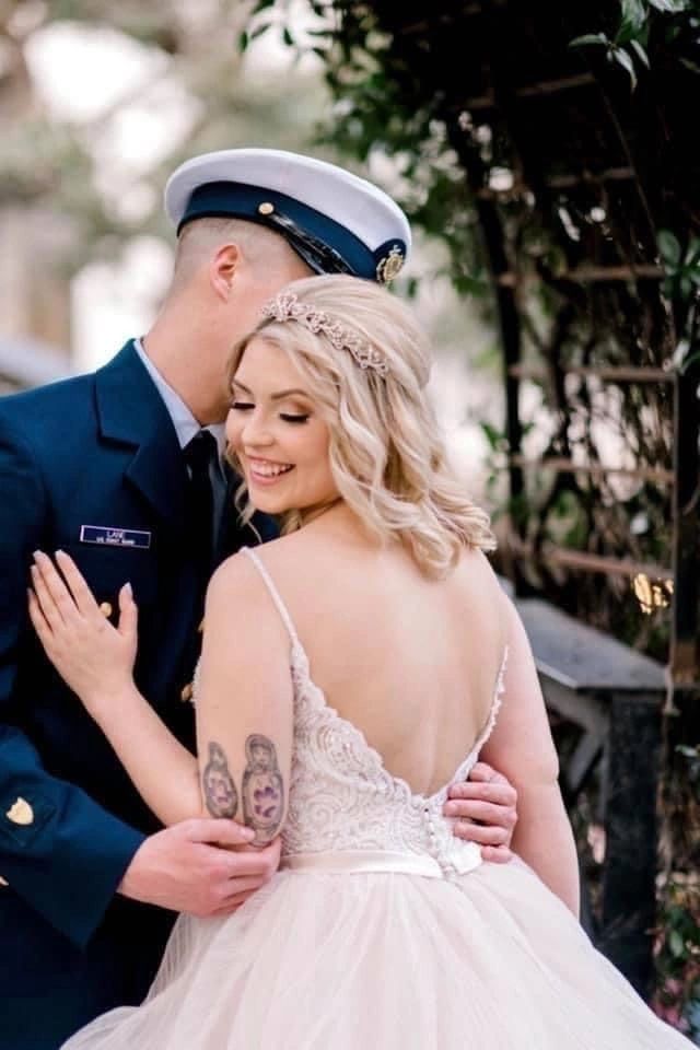 Bride in lace gown with groom in military dress uniform, ivy-covered arch